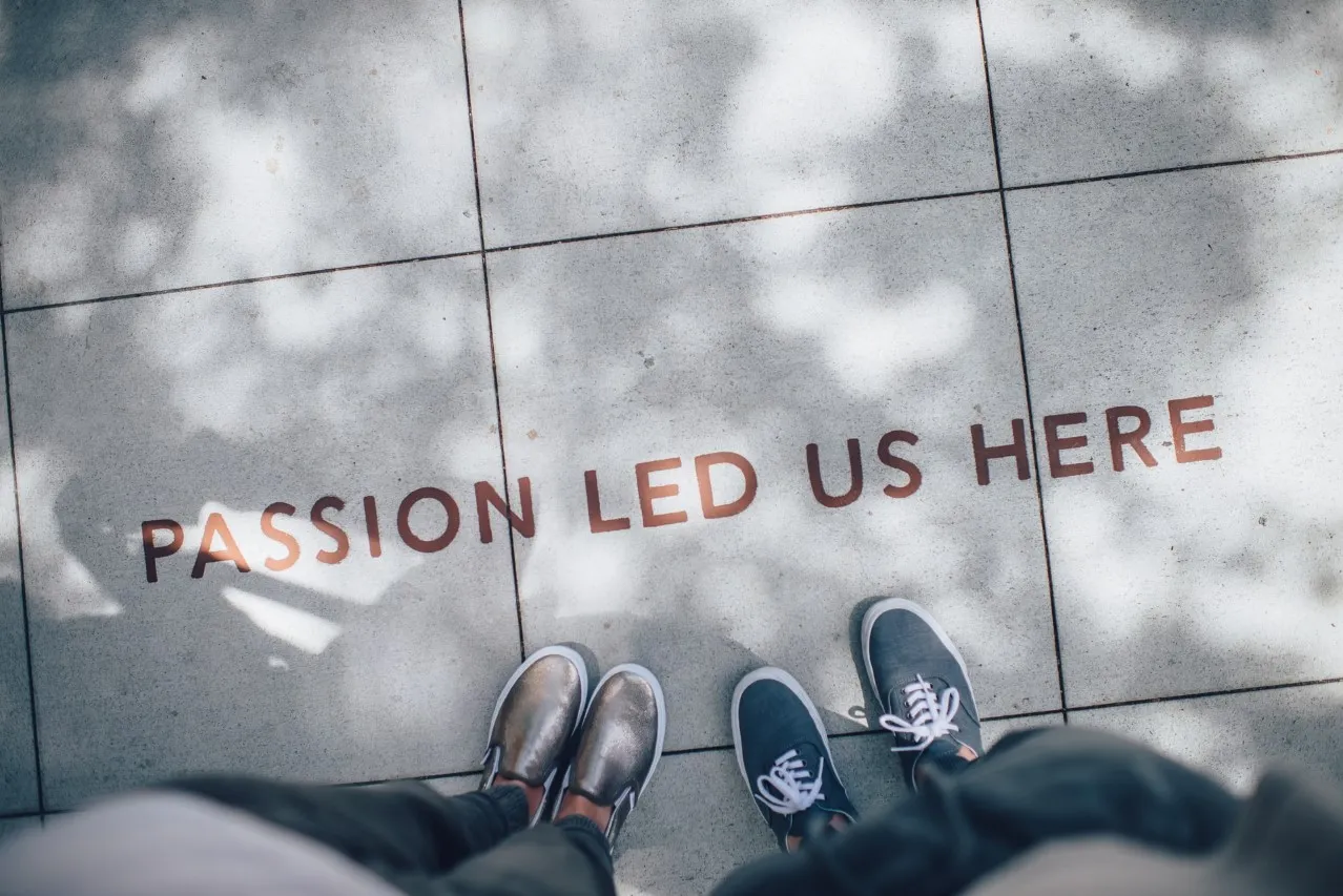 A pair of feet standing in front of a sign that says passion led us here.